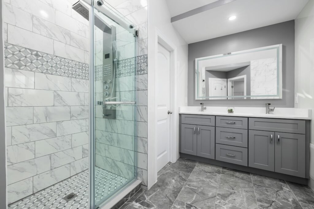 pexels-photo-10827343-10827343 Luxurious modern bathroom featuring grey cabinets and a marble-tiled shower.
